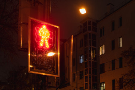 Red traffic light is on for pedestrians. Symbol of standing man as prohibition of crossing city road for pedestrians. road sign at night.の写真素材
