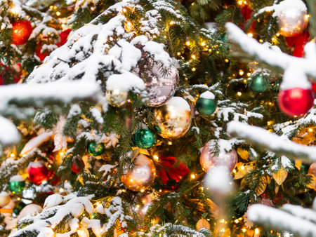 Christmas tree with outdoor decorations. Fir tree decorated with colorful balls and light bulbs for New Year celebration.の写真素材