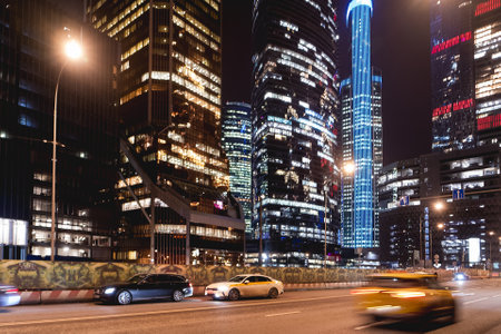 MOSCOW, RUSSIA - November 11, 2022. Yandex Taxi is moving fast on urban road among skyscrapers. Illuminated towers Moscow International Business Center.のeditorial素材
