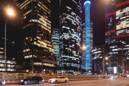 MOSCOW, RUSSIA - November 11, 2022. Yandex Taxi is moving fast on urban road among skyscrapers. Illuminated towers Moscow International Business Center.のeditorial素材