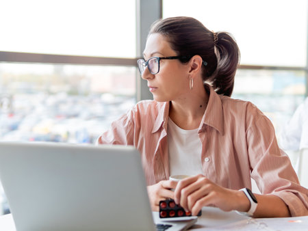 Mindful woman with medicine pills. Working with laptop. Mental health problems, emotional burnout or headache. Modern office at co-working center. Workplace for freelancers or students.の写真素材
