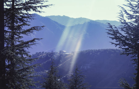 Landscape, sun rays pass through clouds, showing Tyndall Effect, and fall on a house on the hilltop and the valley below.の写真素材