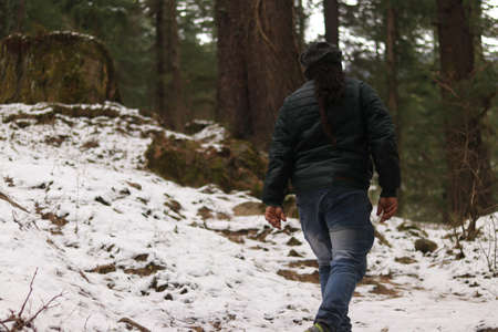 Man with Dreadlock Hair Walks in a Snowy Forest, Explores Surroundings, View from Back, 5Kの写真素材