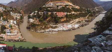 DEVPRAYAG, INDIA - JUNE 9, 2019 : The rivers Bhagirathi (left) and Alaknanda merge together to form the holy river Ganga, going towards far right, in this ancient city, Devprayag, 8Kのeditorial素材