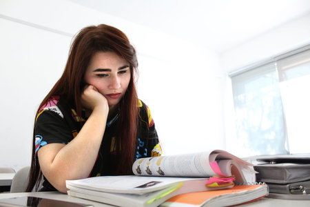 Pretty young girl with long beautiful hair study in university and reading book