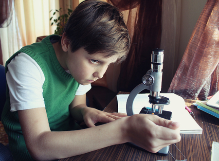 The boy is studying the details under a microscopeの写真素材