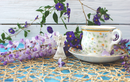 A cup of tea on a wooden blue table with a bouquet of colored field flowersの写真素材