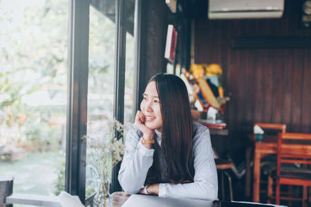 A women using laptop on the table at in cafe shop. She is asian women. She shopping online by laptop or notebook. She siting on the wood table.の写真素材