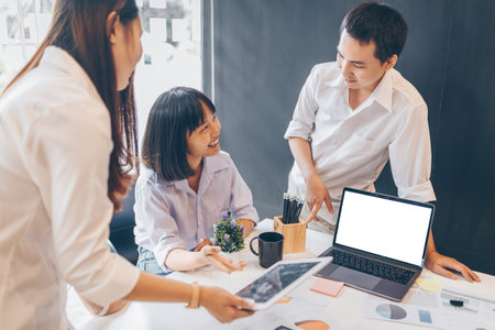 Image of business partners discussing documents and ideas at meeting and have laptop and tablet. on...