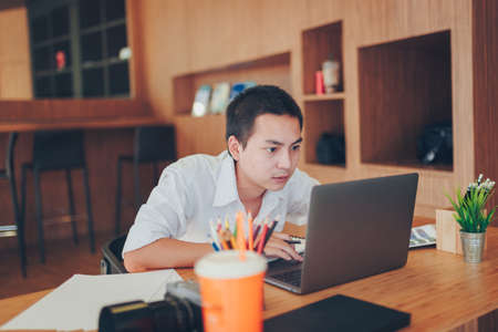 Businessman is serious to looking laptop in office room. He is designer.の写真素材