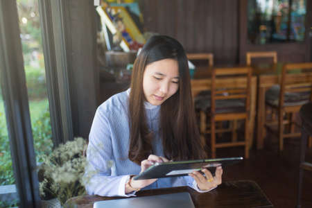 Women sitting and using smartphone and laptop on the table and she is feeling happiness at garden or cafe shop.の写真素材