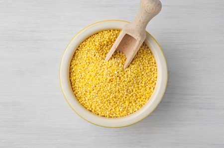 Organic millet seeds in a ceramic bowl on wooden white rustic table.Supergrain with its mildly sweet...