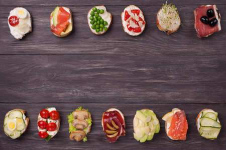 Various canapes prepared with different fillings salmon, cucumber, cherry tomatoes, mozzarella, eggs, mushrooms, olives, avocado, almonds, micro greens.の写真素材