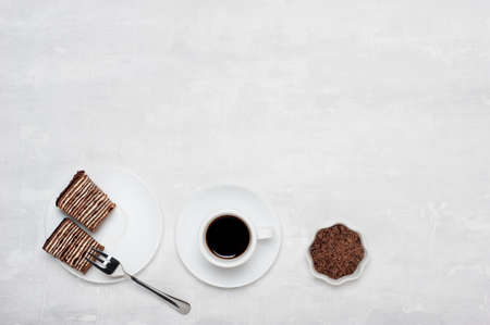Creative layout made of chocolate crumbs, cup with coffee and sweet chocolate cake on light grey background. Flat lay. Food concept.の写真素材