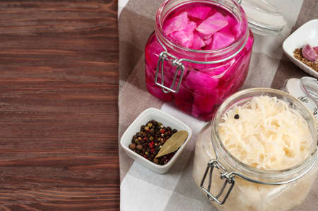Sauerkraut  and beet sauerkraut  in a glass jar on a wooden table with spices and herbs.Probiotics food concept with  space for text.の写真素材