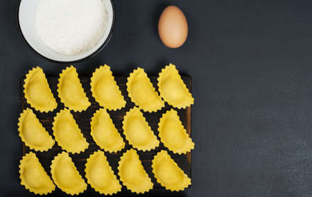 Creative layout made of ucooked ravioli pasta,flour in the bowl and one egg . Horizonta orientation with copy space. Food concept.の写真素材