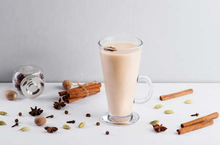 Masala chai or  spiced tea  in glass cup with fresh ginger, cardamom, cinnamon, cloves and star anise that bring you comfort and warmth . Top view, horizontal image, copy space.の写真素材