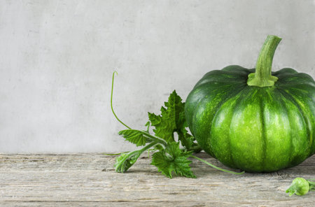 Homegrown organic pumpkin with stem and leaves  wooden background front view.Background with copy...