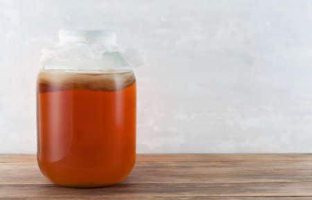 Homemade fermented drink Kombucha in a glass jar on a wooden table.Healthy organic fermented probiotic drink.Healthcare concept  background.Image with copy space.の写真素材