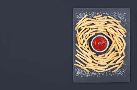 Golden french fries potatoes with ketchup on the gray slate board over gray background.Flat lay with copy space.の写真素材