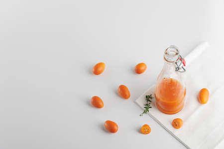 Healthy detox juice made with  tangerines  and kumquats in the glass bottle over white background.Horizontal orientation with space for text.の写真素材