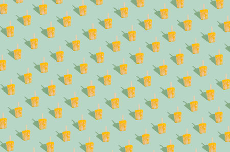 Creative pattern made with yellow sorbet ice cream against pastel mint green background. Minimai...