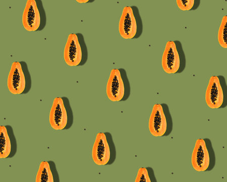 Creative tropical  pattern with orange papaya fruitÂ  andÂ  seeds overÂ  green background....