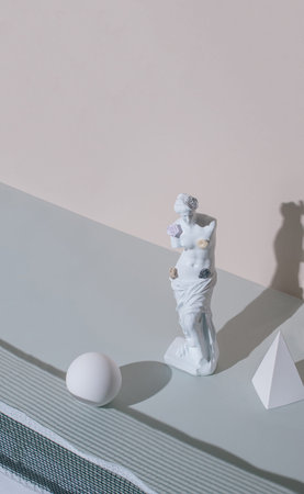 Abstract layout with the sculpture of an antique Venus and geometric shapes on the pastel gray...