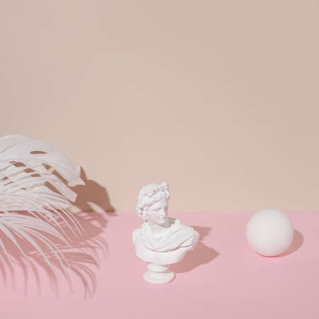 White sculpture of a retro Apollo and  palm leaves on pastel pink against the beige background. Creative minimal vintage background. Retrofuturism.の写真素材