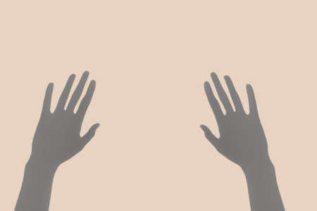 Abstract image of the pair of hand shadows on the pastel  beige background. Minimal surreal style concept.の写真素材