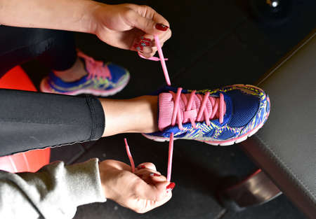 Young girl is tying her shoes for runningの写真素材