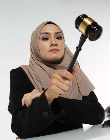 Beautiful Muslim woman Judge wear Hijab striking the gavel on a desk. Justice and Law Conceptの写真素材