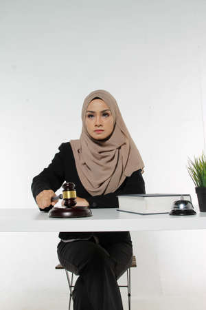 Beautiful Muslim woman Judge wear Hijab striking the gavel on a desk. Justice and Law Conceptの写真素材