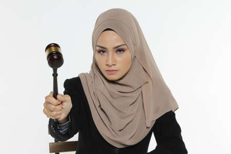 Beautiful Muslim woman Judge wear Hijab striking the gavel on a desk. Justice and Law Conceptの写真素材