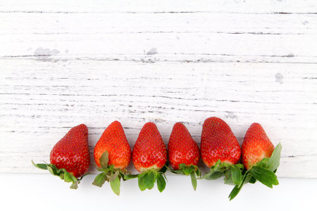 Close up row of Fresh healthy fruits Strawberries with leaves over wooden texture background. Copy...