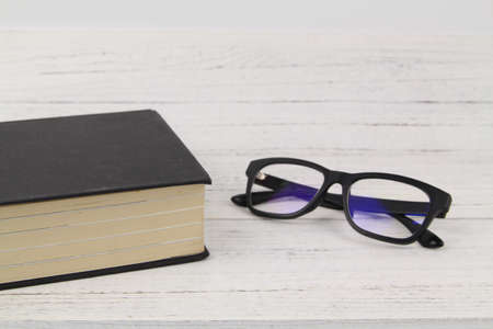 Close up Black Eye Glasses with a thick black book over wooden texture background. Copy Space conceptの写真素材
