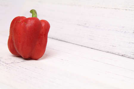 Fresh red bell capsicum peppers on a bright wooden backgroundの写真素材