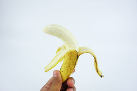Hand holding a peel banana isolated white background. Healthy nutritious Food.