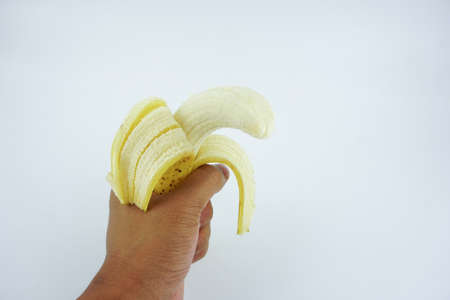 Hand holding a peel banana isolated white background. Healthy nutritious Food.の写真素材