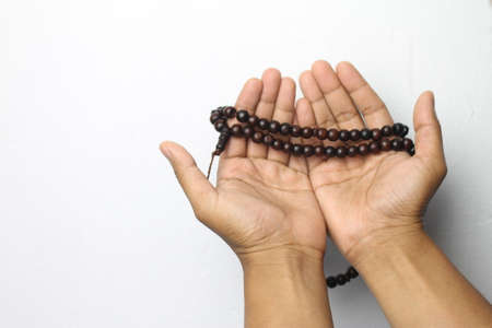 Male hand holding muslim beads rosery or tasbih over white background.の写真素材