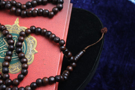 Close up Holy Quran with tasbih or muslim beads rosery over a praying mat. Ramadan Kareem