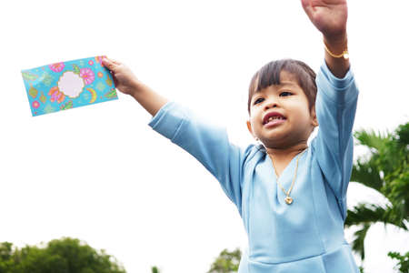 A Malay Girl in Malay traditional cloth showing his happy reaction after received money pocket during Hari Raya celebration. On the money pocket written with Selamat Hari Raya or Happy New Yearの写真素材