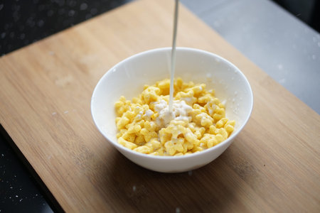 Star Shape Cereal for Breakfast on a White Bowl over wooden plate pouring a dairy milk. Healthy Food...