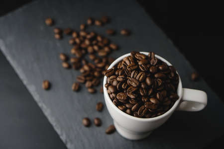 Flat lay of Coffee bean on white cup over a stone rock slate background. Celebrate October coffee Day. Copy space Conceptの写真素材