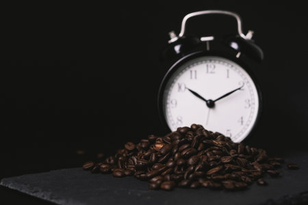 vintage alarm clock and coffee beans on slate stone plate. Seletive Focus. Copy Space concept....