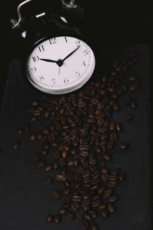 vintage alarm clock and coffee beans on slate stone plate. Seletive Focus. Copy Space concept. Celebrate International Coffee Day On Octoberの写真素材