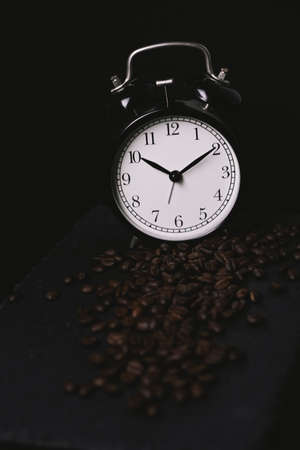 vintage alarm clock and coffee beans on slate stone plate. Seletive Focus. Copy Space concept. Celebrate International Coffee Day On Octoberの写真素材