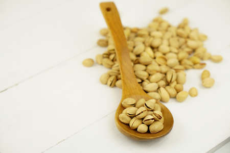 Close up Pistachio on white wooden background and spoon. Selective focus. Copy Spaceの写真素材