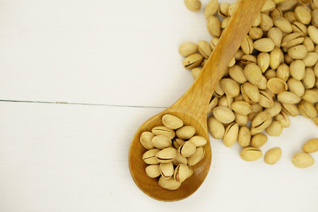 Close up Pistachio on white wooden background and spoon. Selective focus. Copy Space