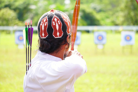 Archery wearing traditional dress target ring and out of focus archer with a bow in the foreground during an archery competitionの写真素材
